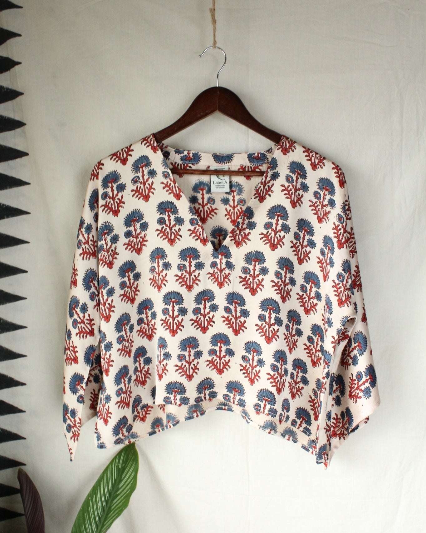 Floral patterned blouse on a hanger against a white wall