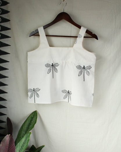 White tank top with black dragonfly designs on a hanger against a white background